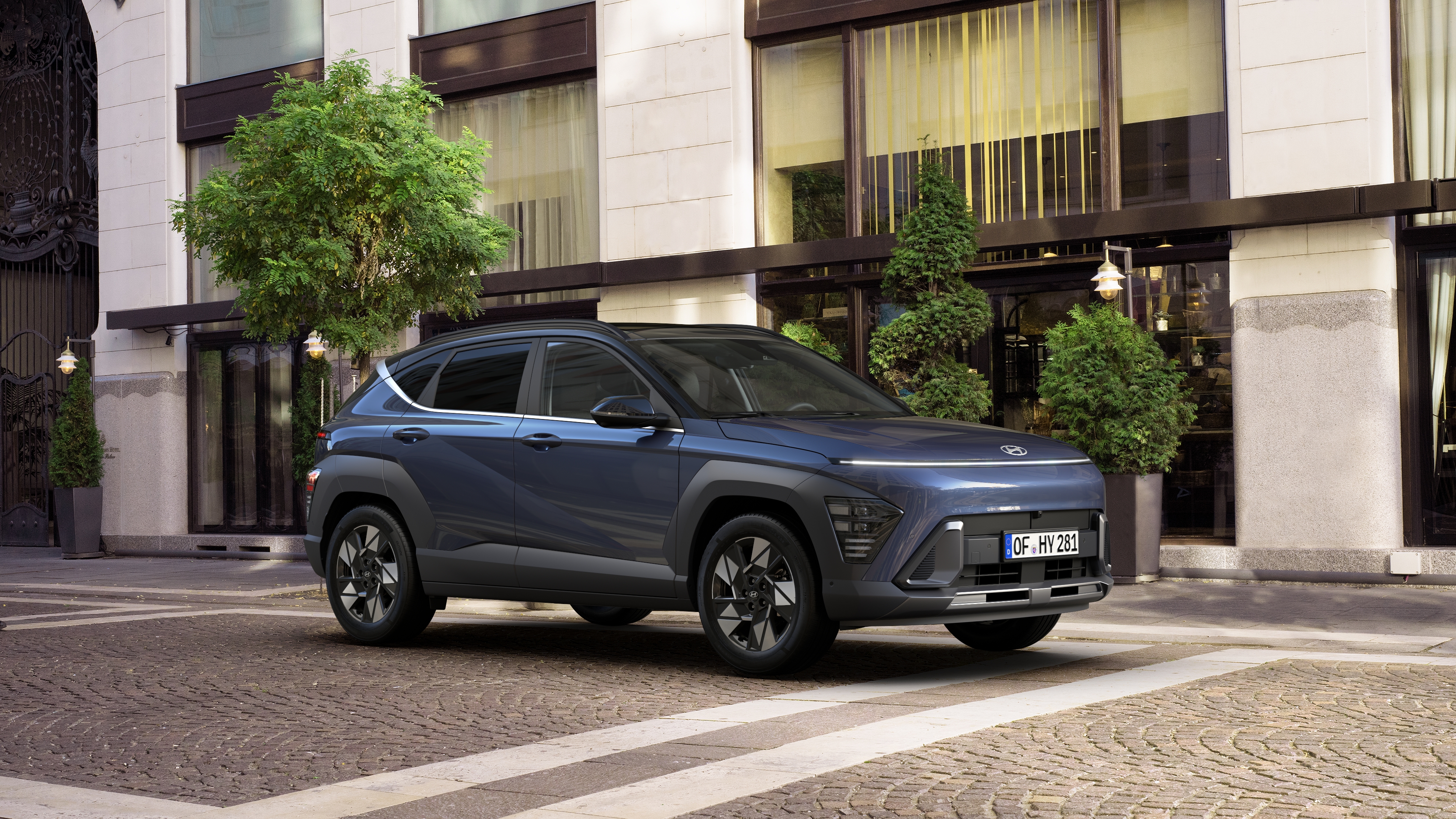 The all-new Hyundai KONA Hybrid pictured from the side in front of a modern building. 