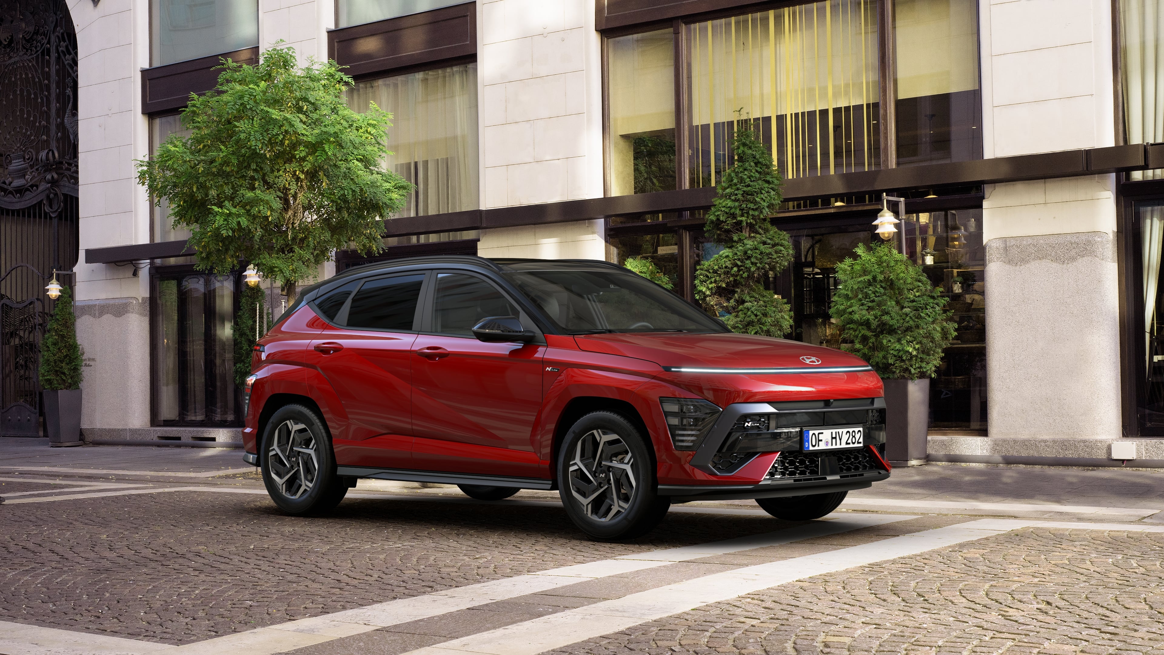 The all-new KONA N Line in red parked next to a modern building.