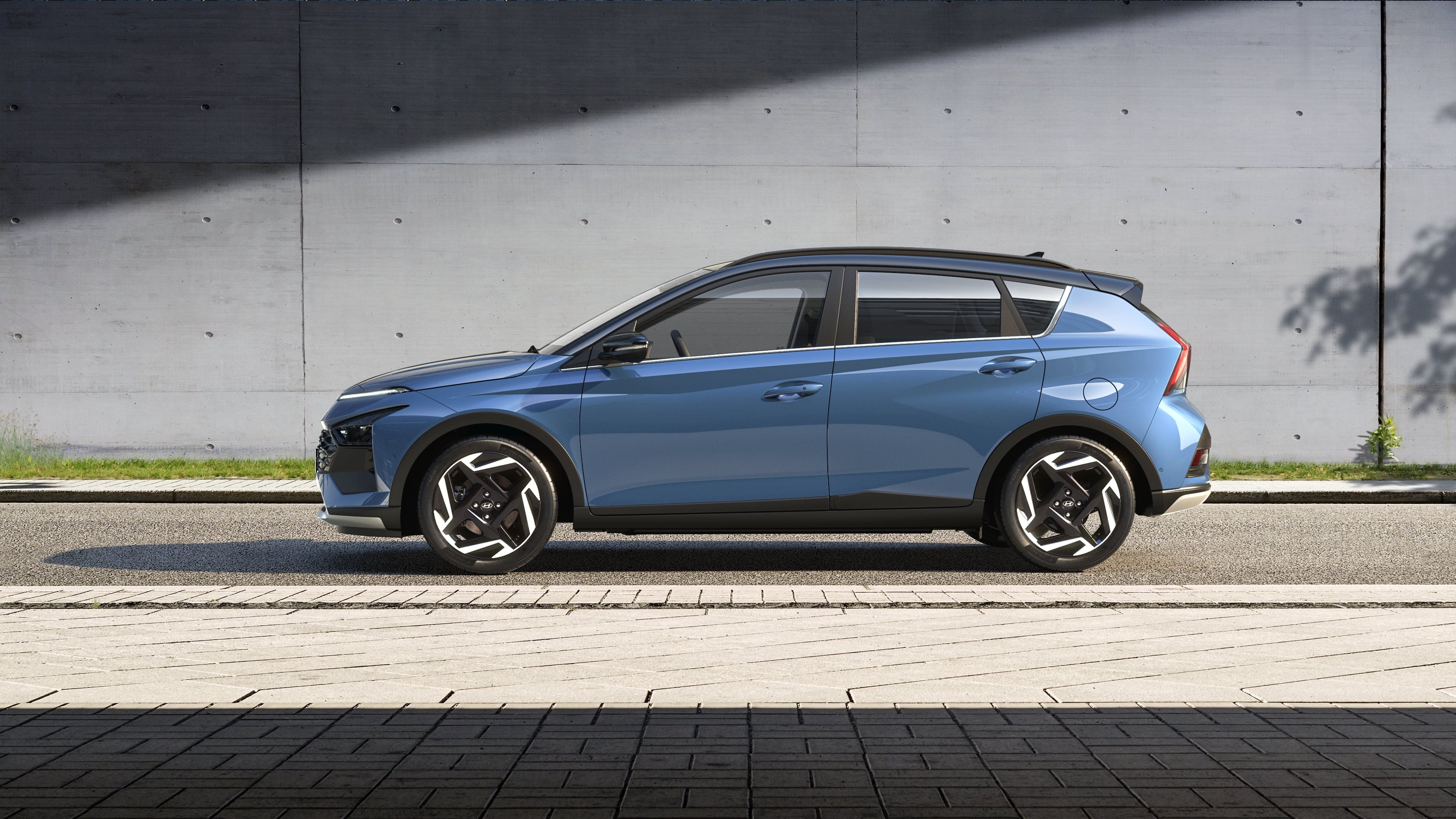 Side view of the blue Hyundai BAYON driving on a street. 