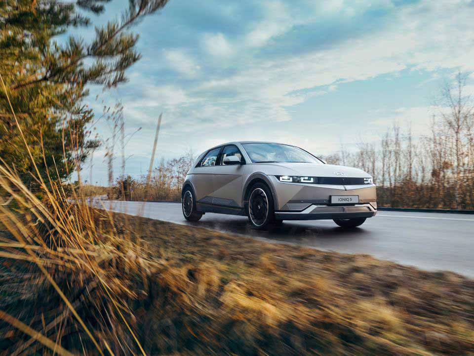 A Hyundai IONIQ 5 electric midsize CUV passing another car on a country road.