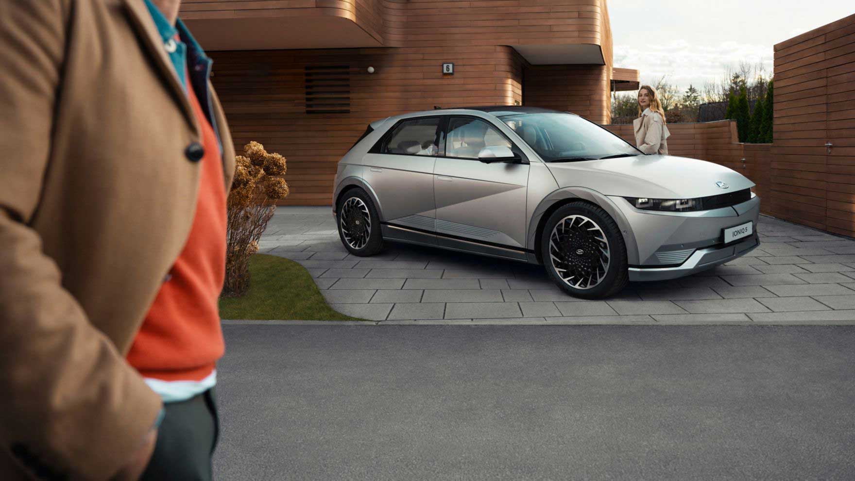 The Hyundai IONIQ 5 electric midsize CUV parked in the driveway of a modern residential building.