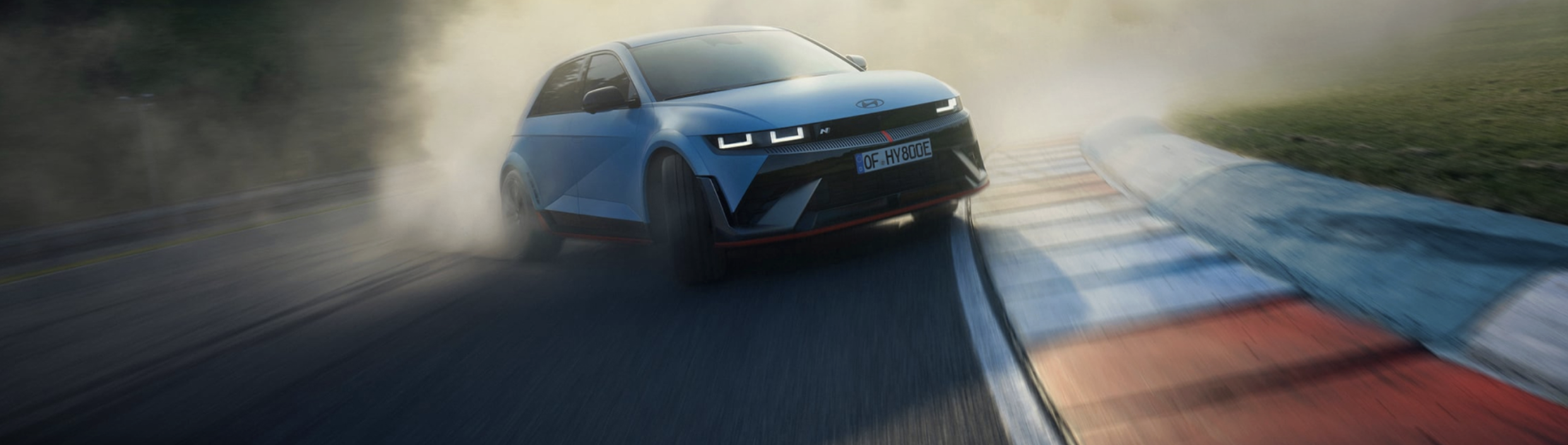 The all-electric Hyundai IONIQ 5 N drifting through a curve on a racetrack with smoking tyres.