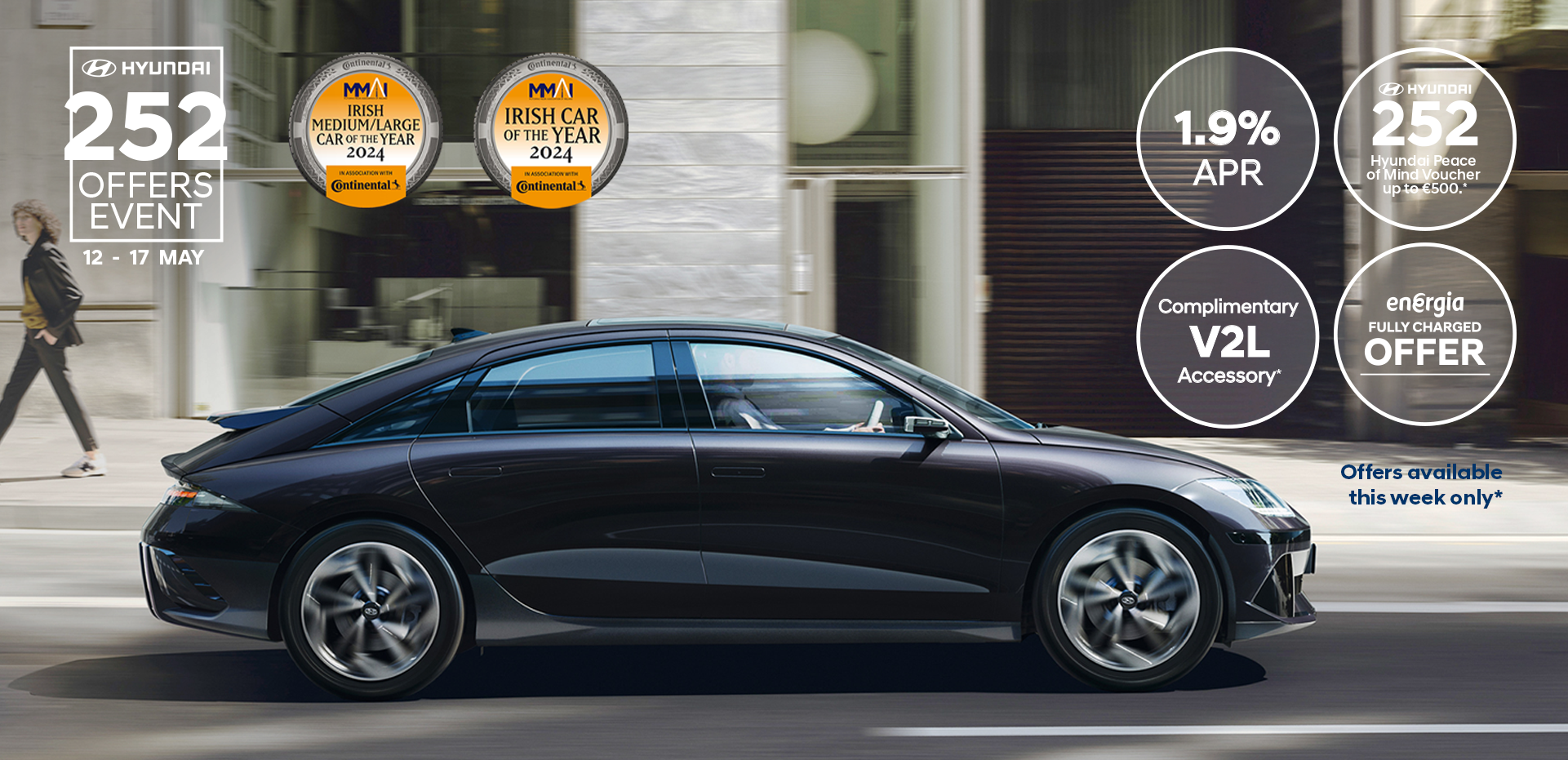 The all-electric Hyundai IONIQ 6 charging in a city with a man leaning on it with an ice cream.