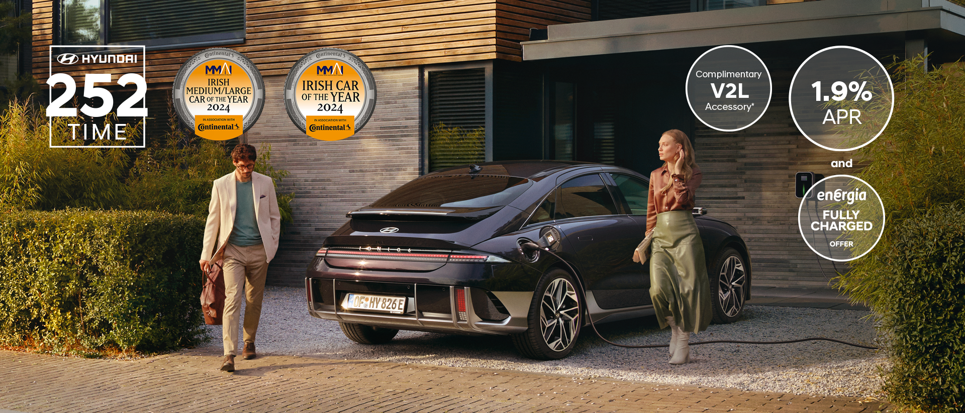 The all-electric Hyundai IONIQ 6 charging in a city with a man leaning on it with an ice cream.