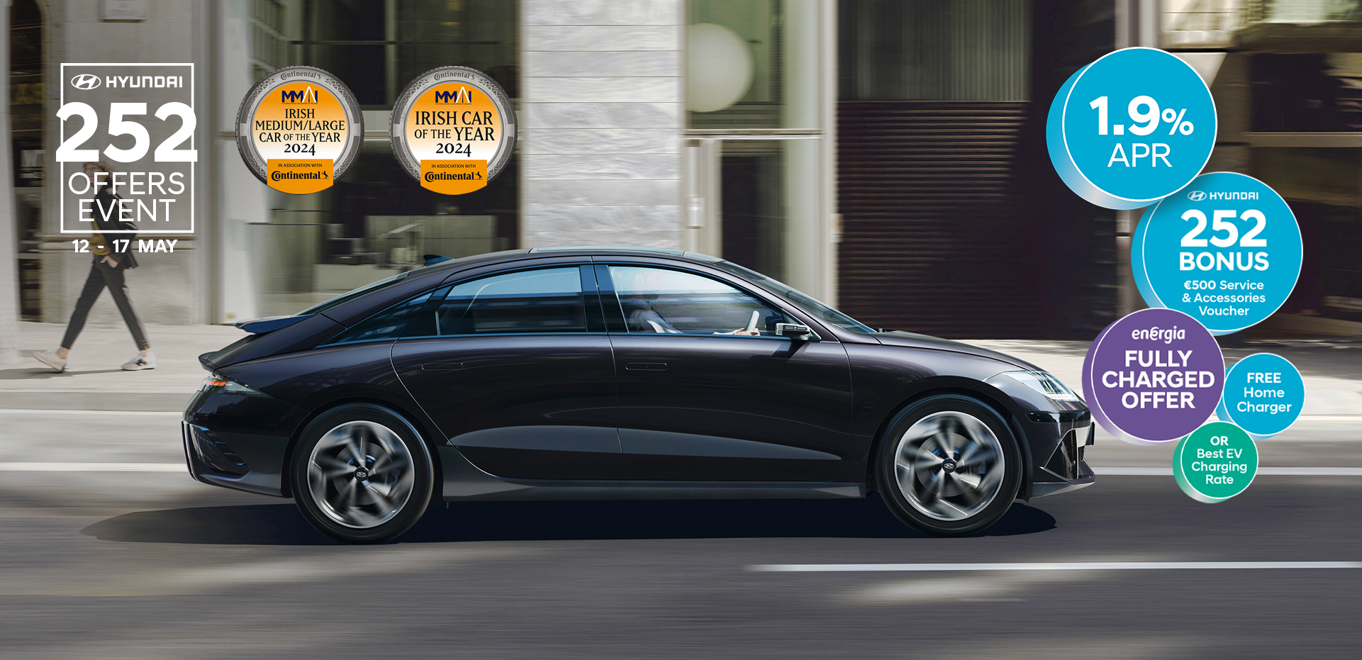 The all-electric Hyundai IONIQ 6 charging in a city with a man leaning on it with an ice cream.