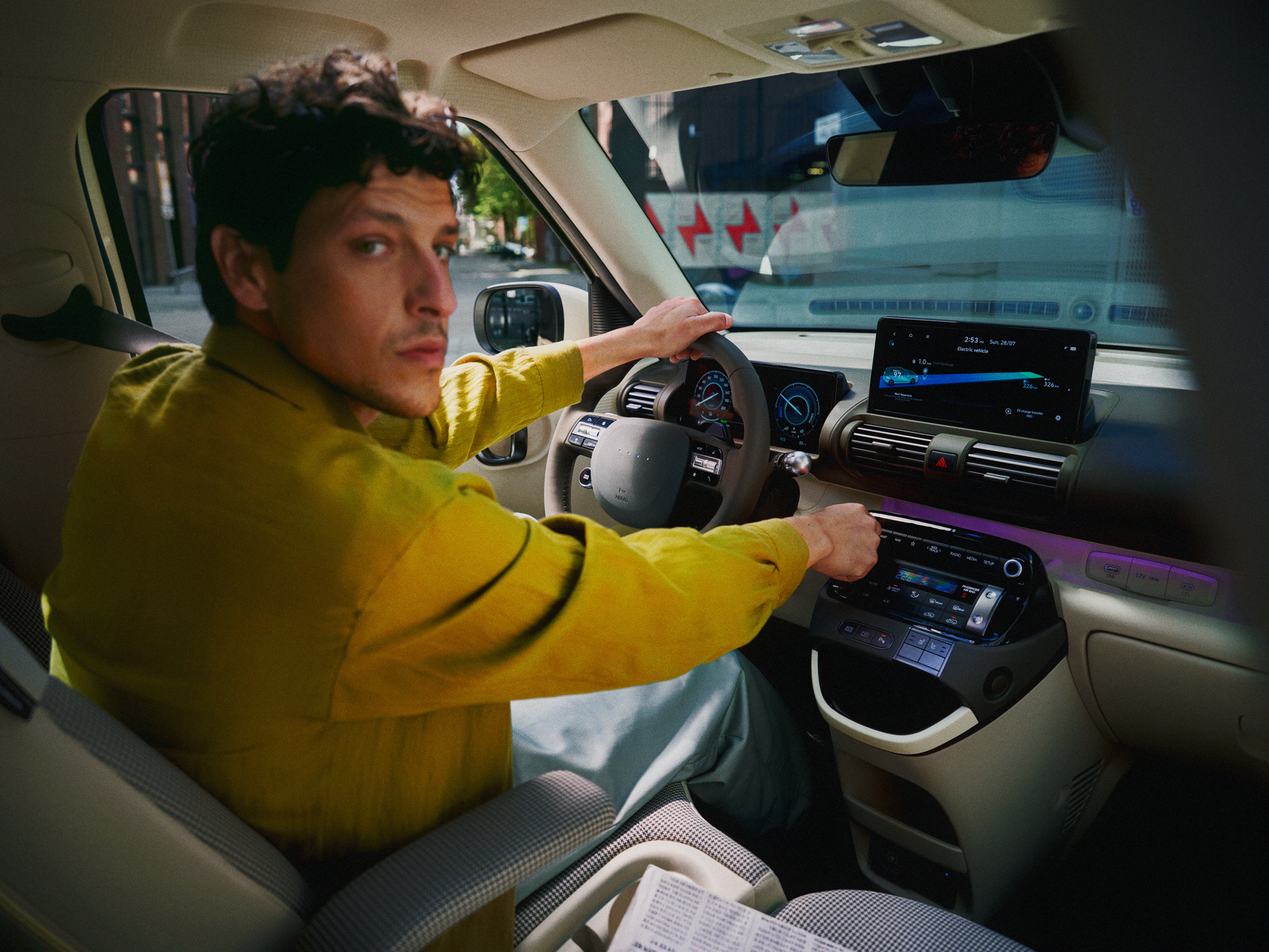 A man sitting in the driver's seat of the new Hyundai INSTER small electric car.