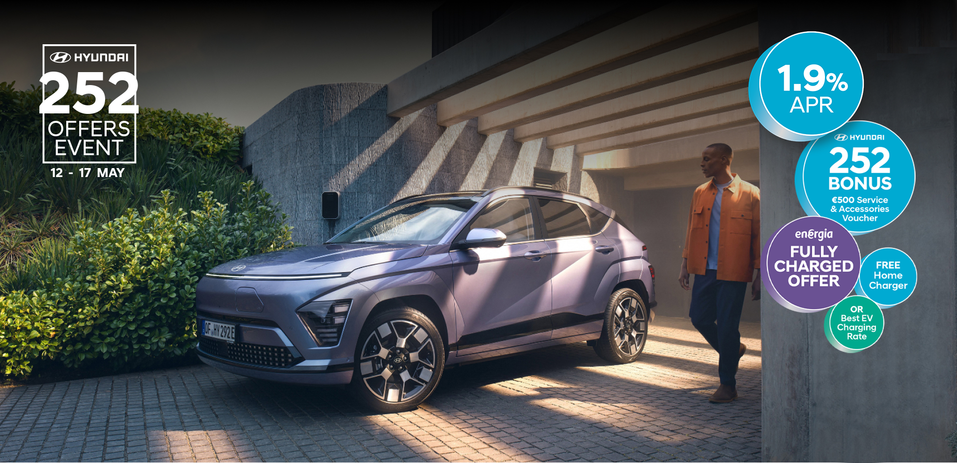 The Hyundai KONA Electric bathed in sunlight with a man walking away from a garage.