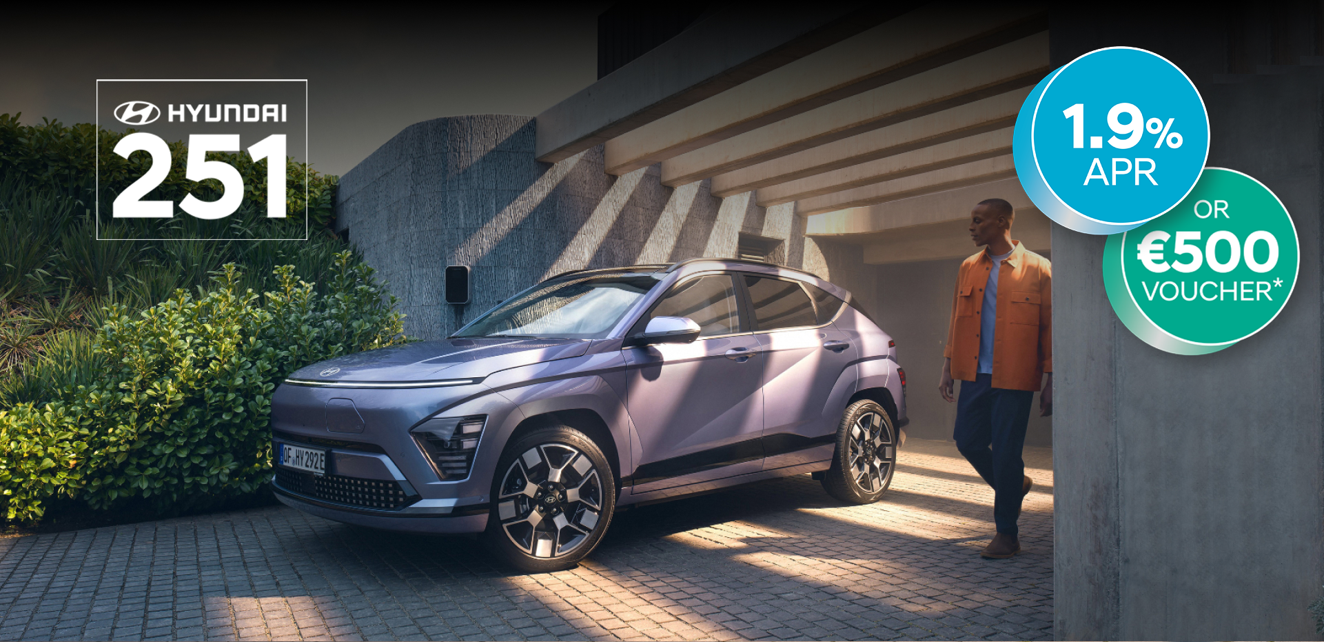 The Hyundai KONA Electric bathed in sunlight with a man walking away from a garage.