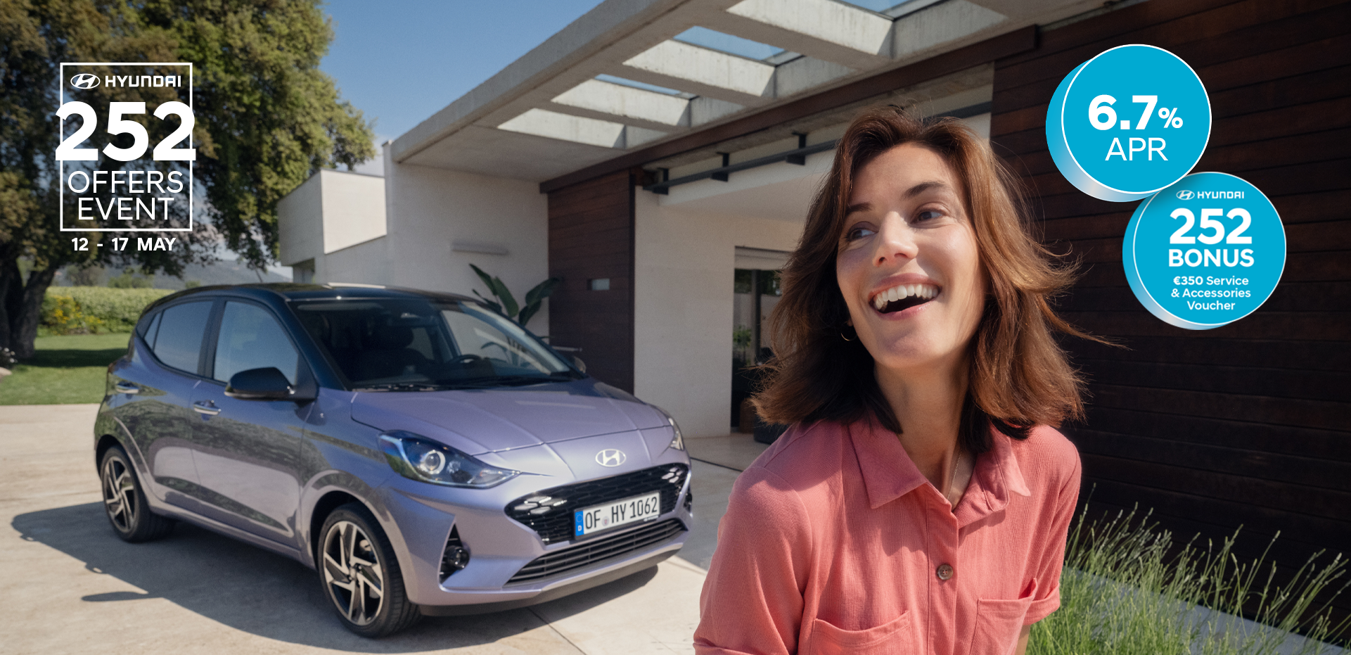 A woman walking and smiling in front of the new Hyundai i10.