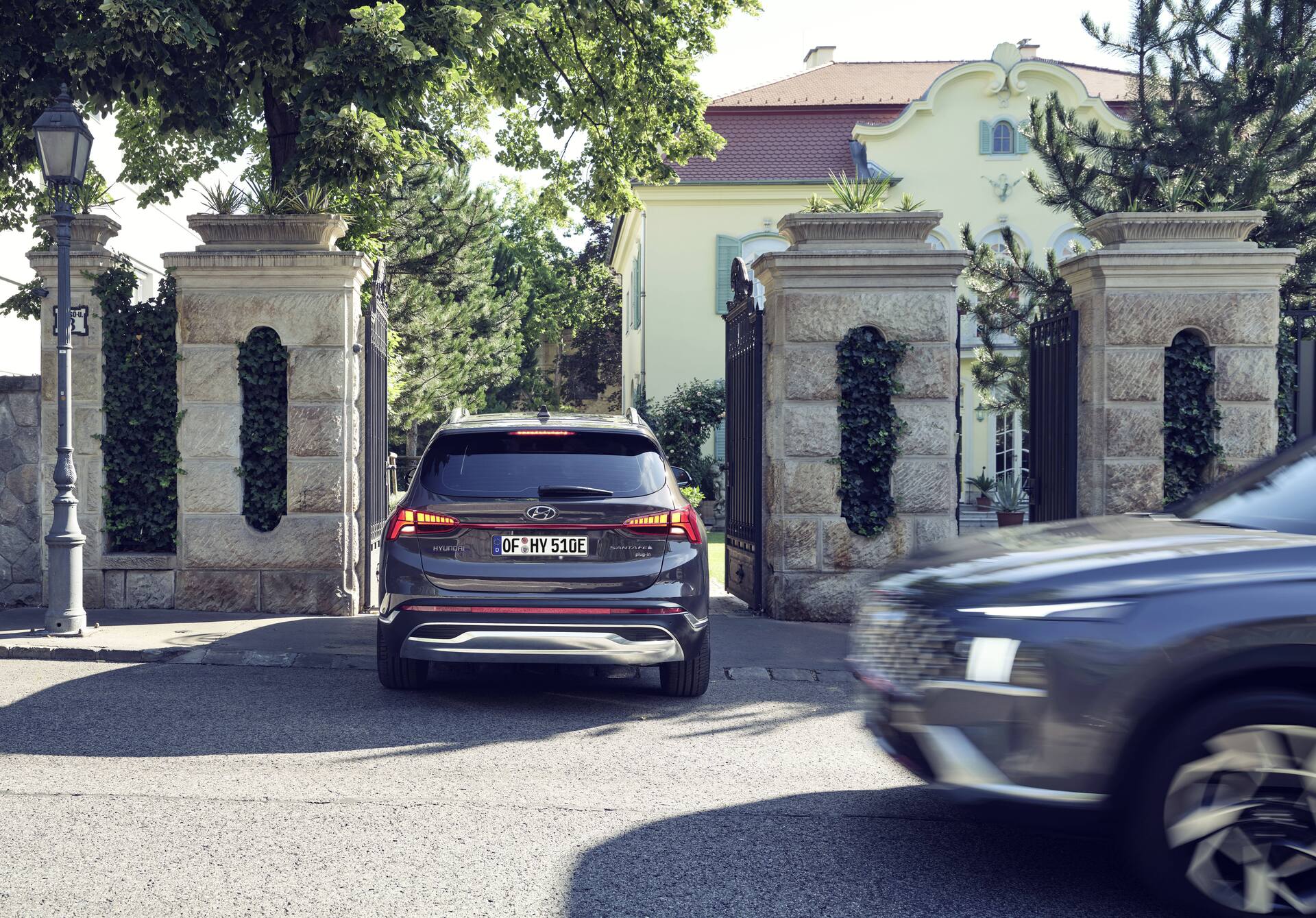 Hyundai Santa Fe Plug-in Hybrid 7 seat SUV driving through an entrance gate of a house.