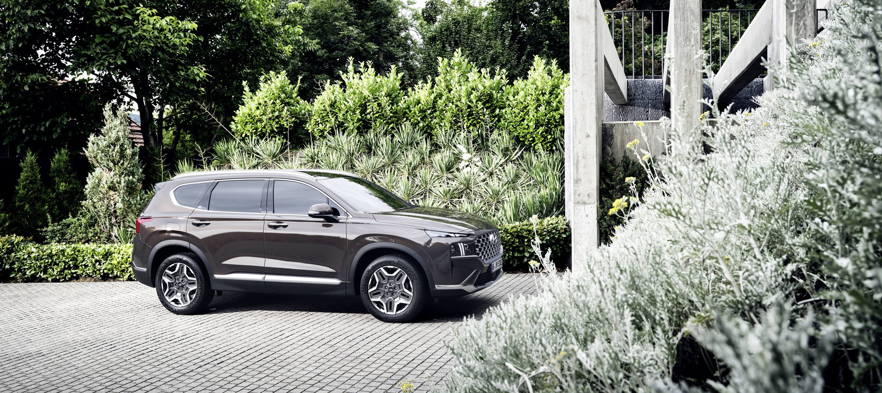 Hyundai Santa Fe Plug-in Hybrid 7 seat SUV driving through an entrance gate of a house.