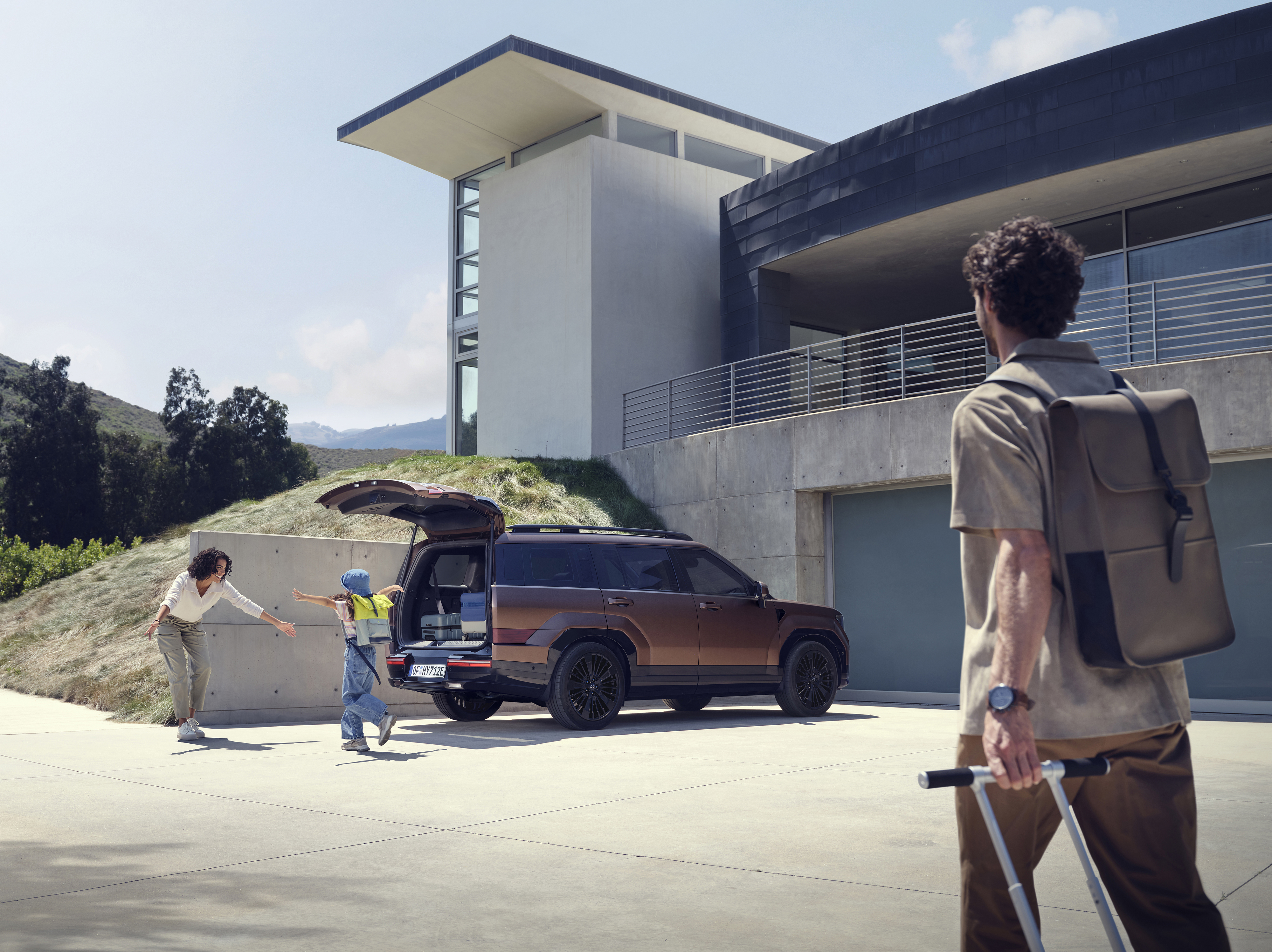  A woman hugging a kid in front of the Hyundai Santa Fe and its large open tailgate.