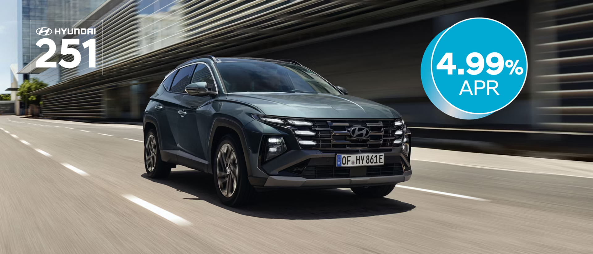 The Hyundai TUCSON Plug-in Hybrid driving down a city street with modern buildings visible.